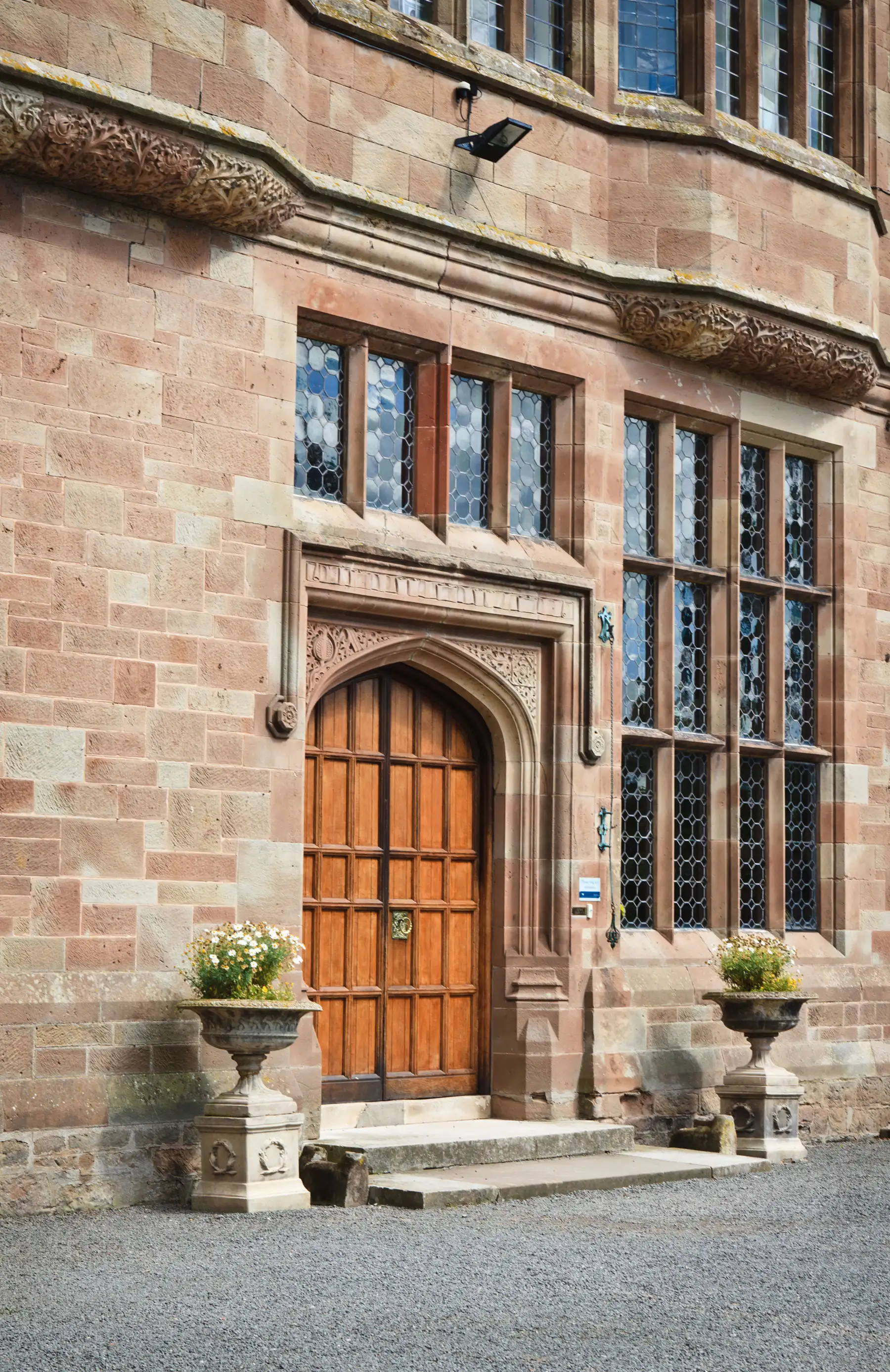 Historic entrance door and stone facade of Adcote Hall